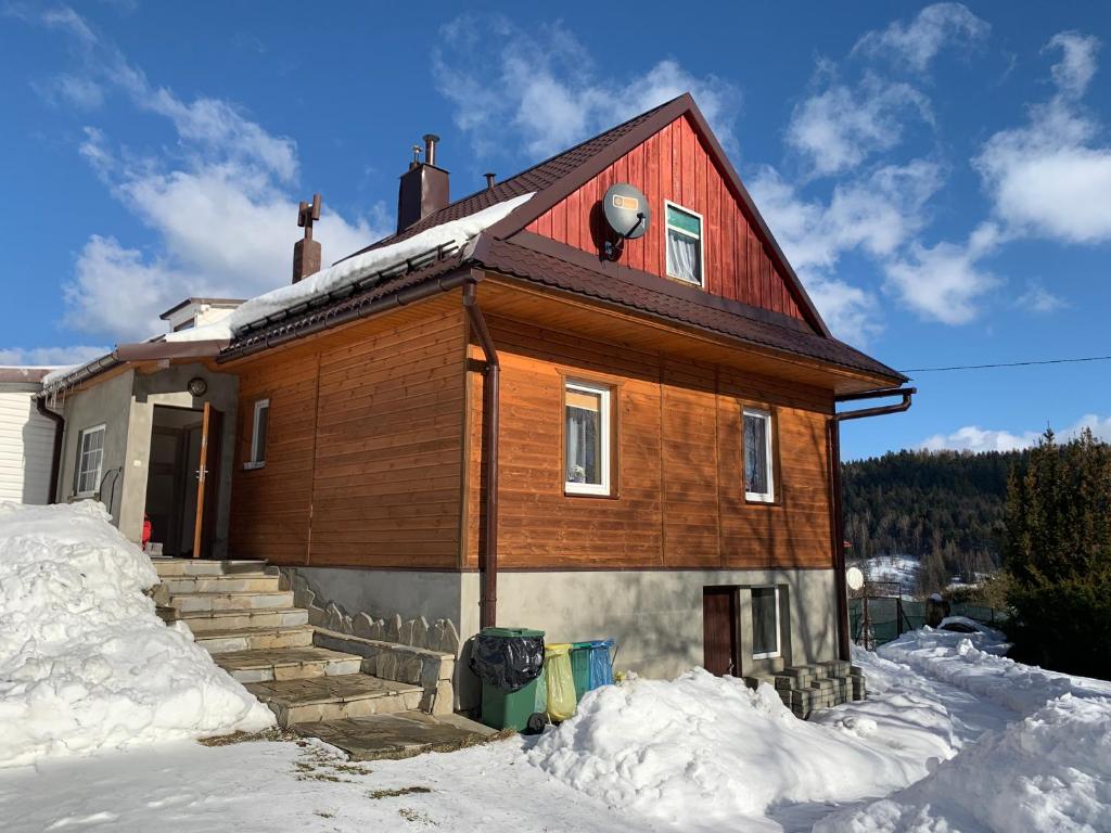 ein Haus mit rotem Dach im Schnee in der Unterkunft Lochówka - zaciszny domek w górach in Krynica-Zdrój