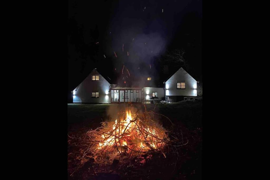 un feu devant une maison la nuit dans l'établissement Bear Cottage, Tyn Y Cwm, à Scyborycoed
