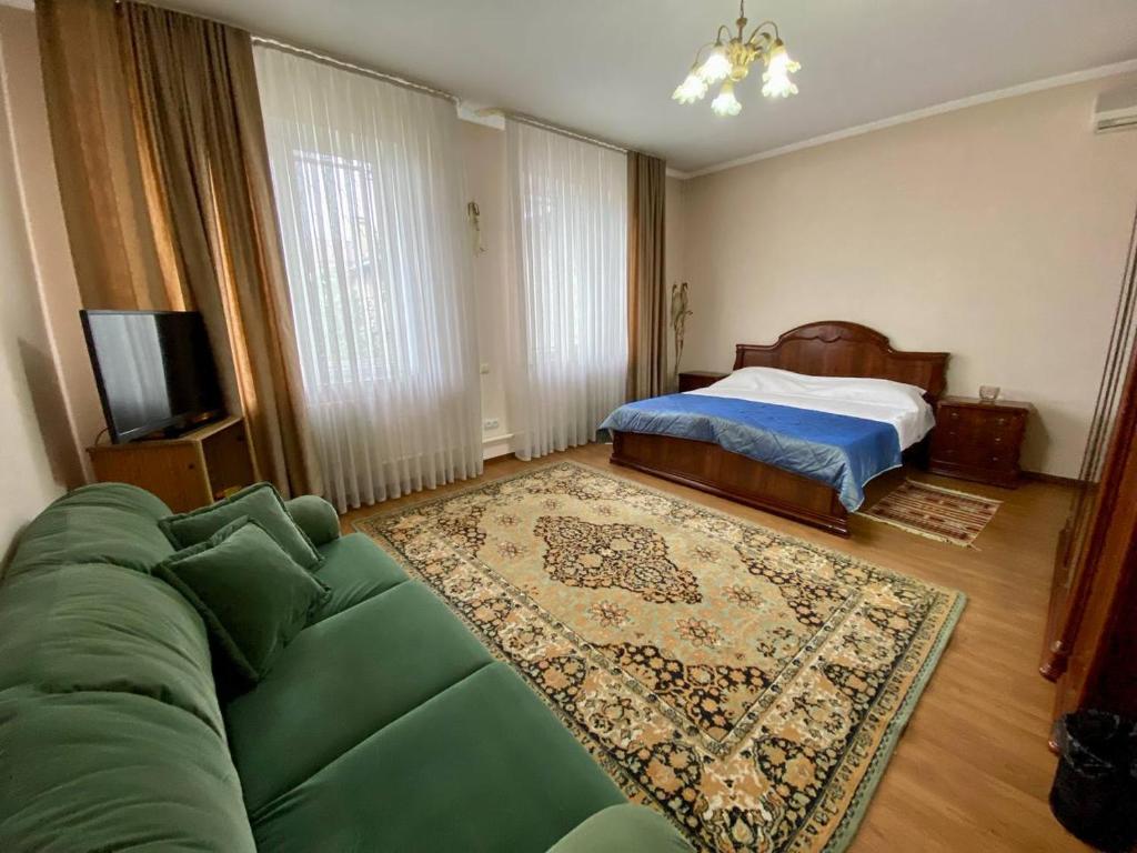 - un salon avec un canapé vert et un lit dans l'établissement Guest House Botanika, à Bishkek