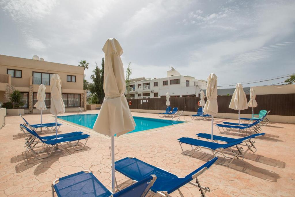 - une piscine avec des chaises bleues et des parasols blancs dans l'établissement Ayia Napa Holiday Apartment Na101, à Ayia Napa