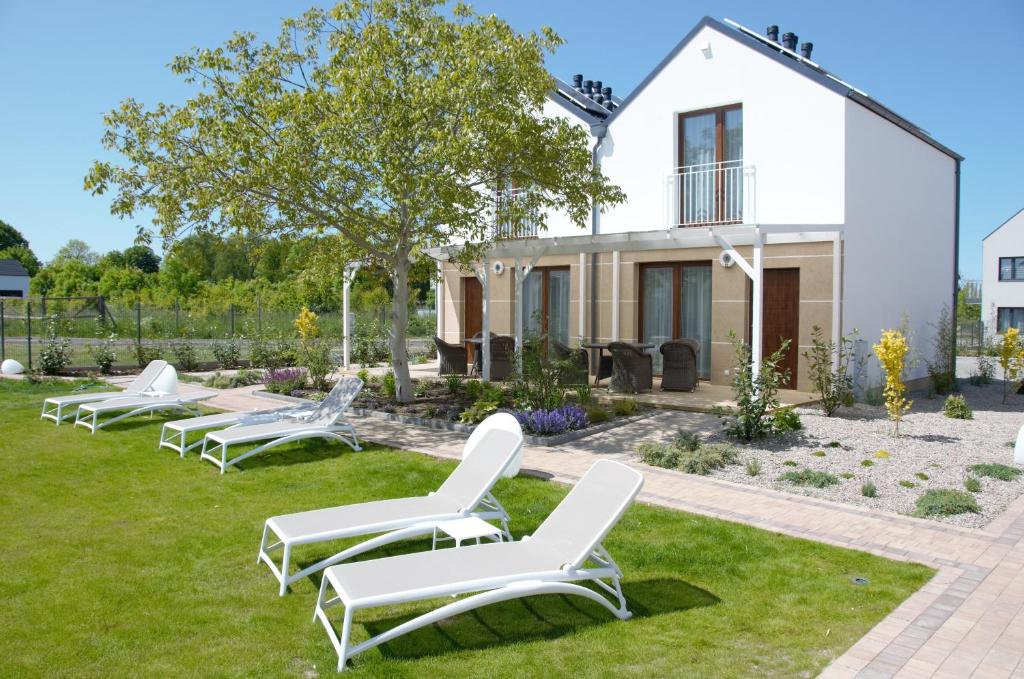 a row of white chairs on a lawn in front of a house at Domki Luan Village in Władysławowo