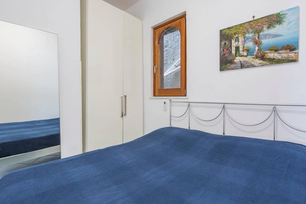 una camera con un letto blu e un dipinto sul muro di La Terrazza Amalfi ad Amalfi