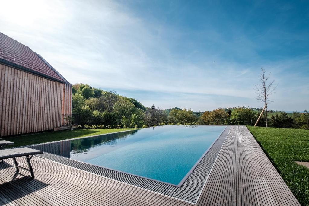 a swimming pool with a wooden deck next to a house at Ferienhaus Greith79 in Kitzeck im Sausal