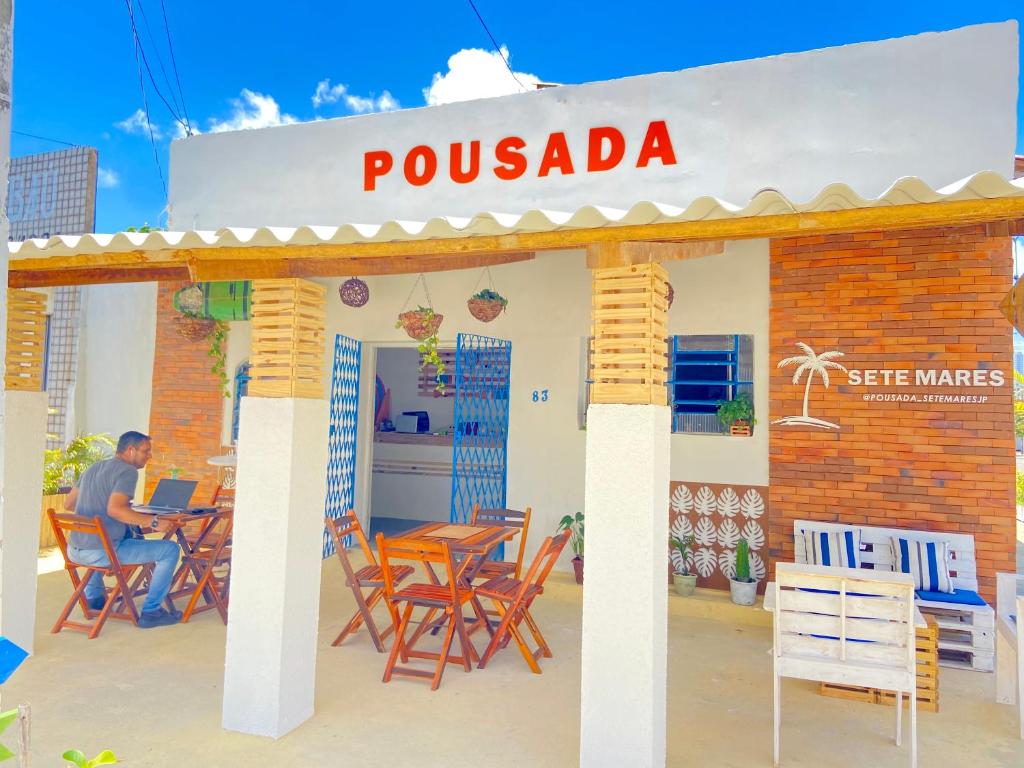 un hombre sentado en una mesa fuera de un restaurante en Pousada Sete Mares, en João Pessoa