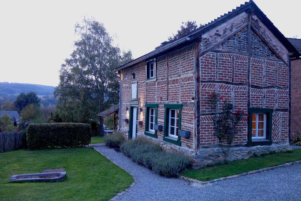 een oud bakstenen huis met een tuin ervoor bij Le Fournil de Hourt in Vielsalm