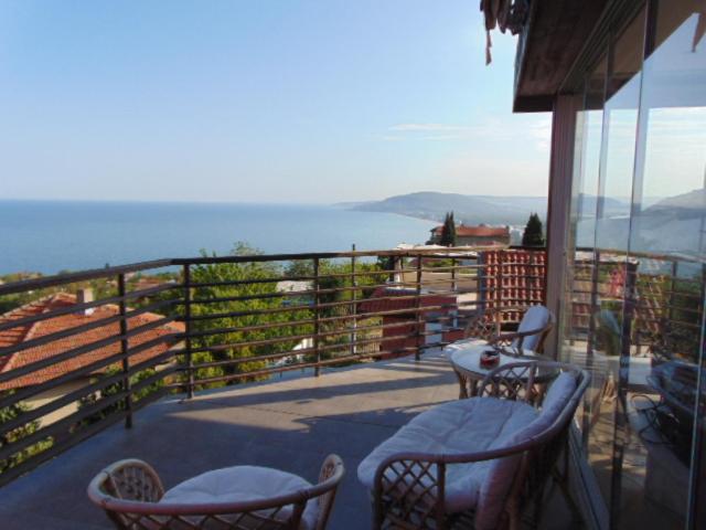 Un balcón con sillas y mesas y vistas al océano. en Къща за гости '' СКАЙ ВЮ '', en Fish Fish