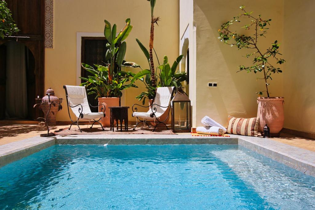 a swimming pool with two chairs and a table at Riad du Ciel Marrakech in Marrakesh