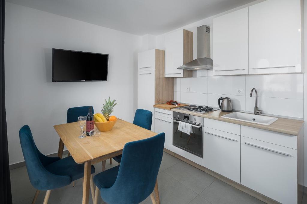 a kitchen with a wooden table and blue chairs at Apartments Špadići in Poreč