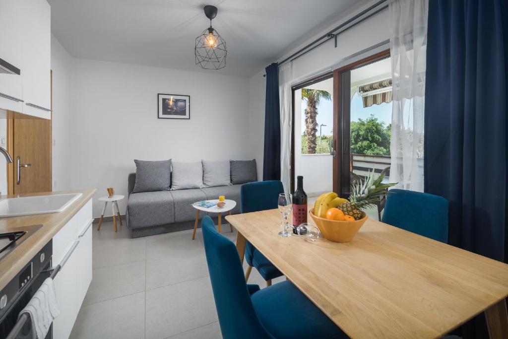 a kitchen and dining room with a wooden table and blue chairs at Apartments Špadići in Poreč