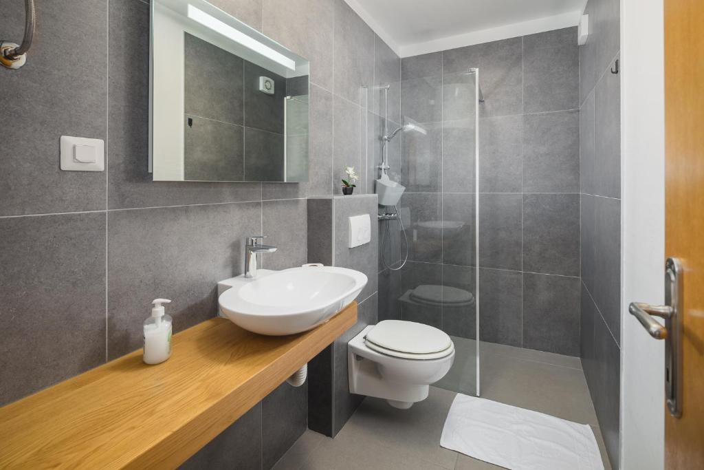 a bathroom with a sink and a toilet and a shower at Apartments Špadići in Poreč