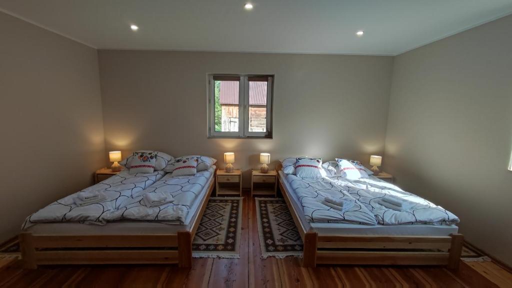 Zimmer mit 2 Betten, einem Tisch und einem Fenster in der Unterkunft Domek u Litwinów in Lipowiec