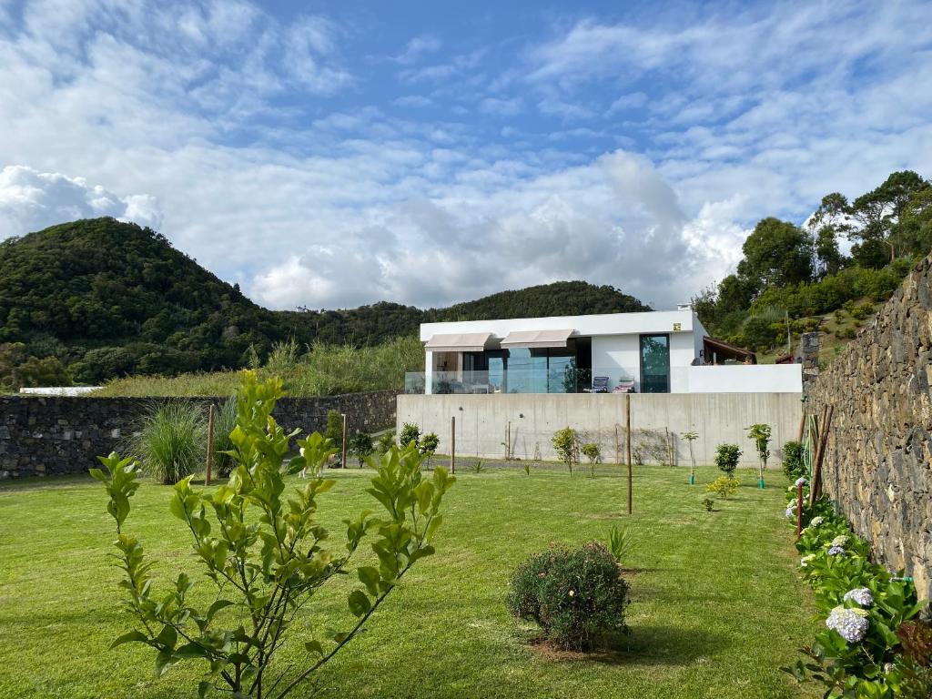 una casa en un campo con una pared de piedra en CaLoura 76 en Lagoa