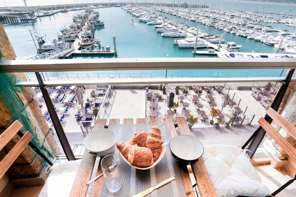 a table with a bowl of bread and a marina at Les Ebihens - Studio et chambre indépendante in Saint-Cast-le-Guildo