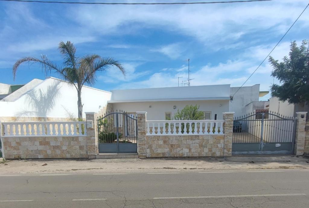 a white house with a fence and a palm tree at SEA ROOM A TORRE LAPILLO - Guest House in Torre Lapillo