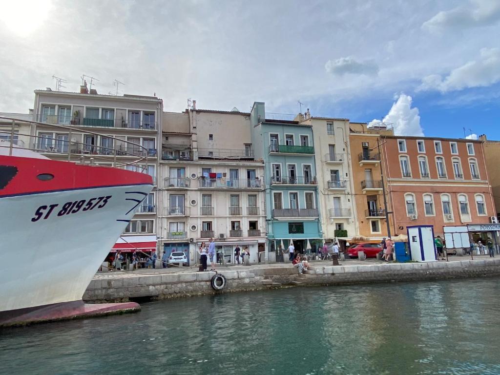 a boat sitting in the water next to some buildings at Le Petit Bijou Sète, quatre appartements au centre ville, trois avec vue canal in Sète