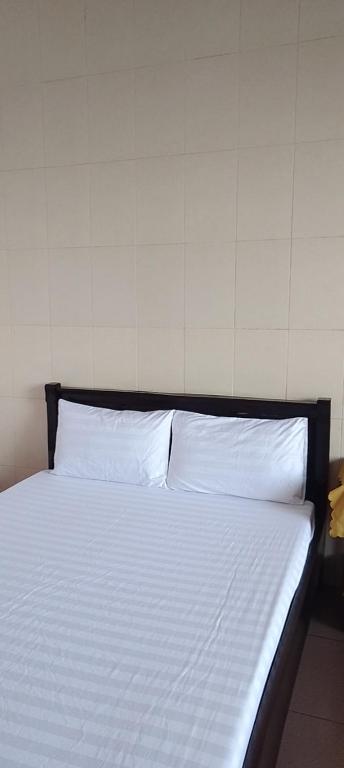 een bed met witte lakens en kussens in een kamer bij Nhà nghỉ Hằng Nga in Dong Hoi