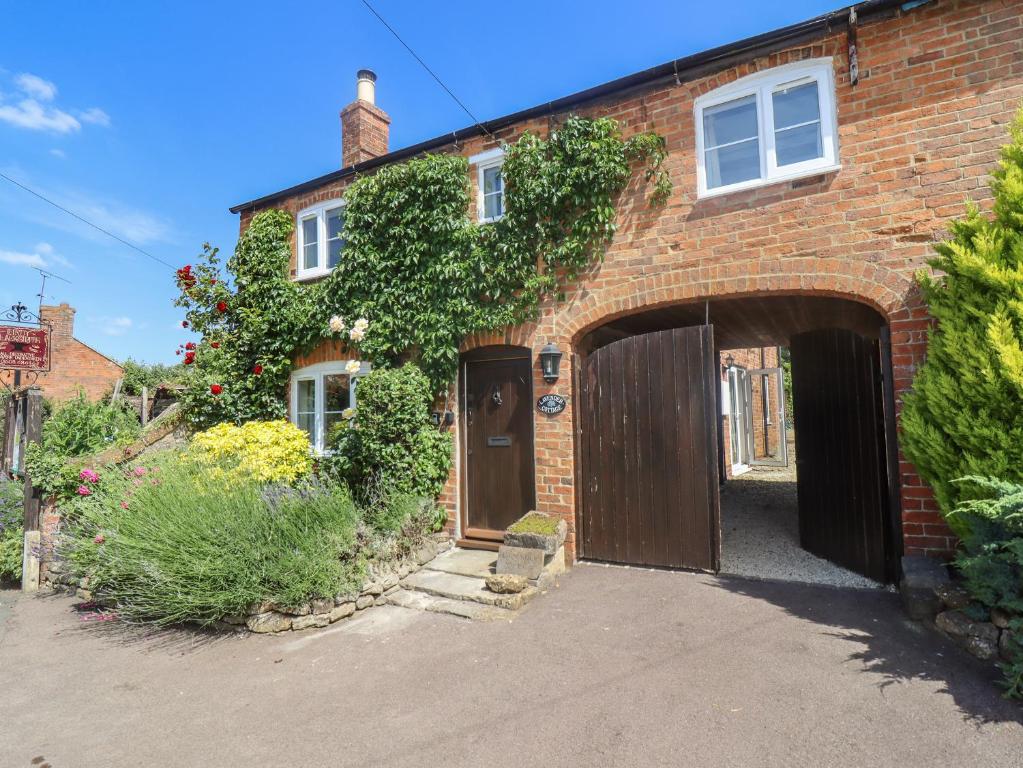 a brick house with a large wooden garage at Lavender Cottage, Brailes in Lower Brailes
