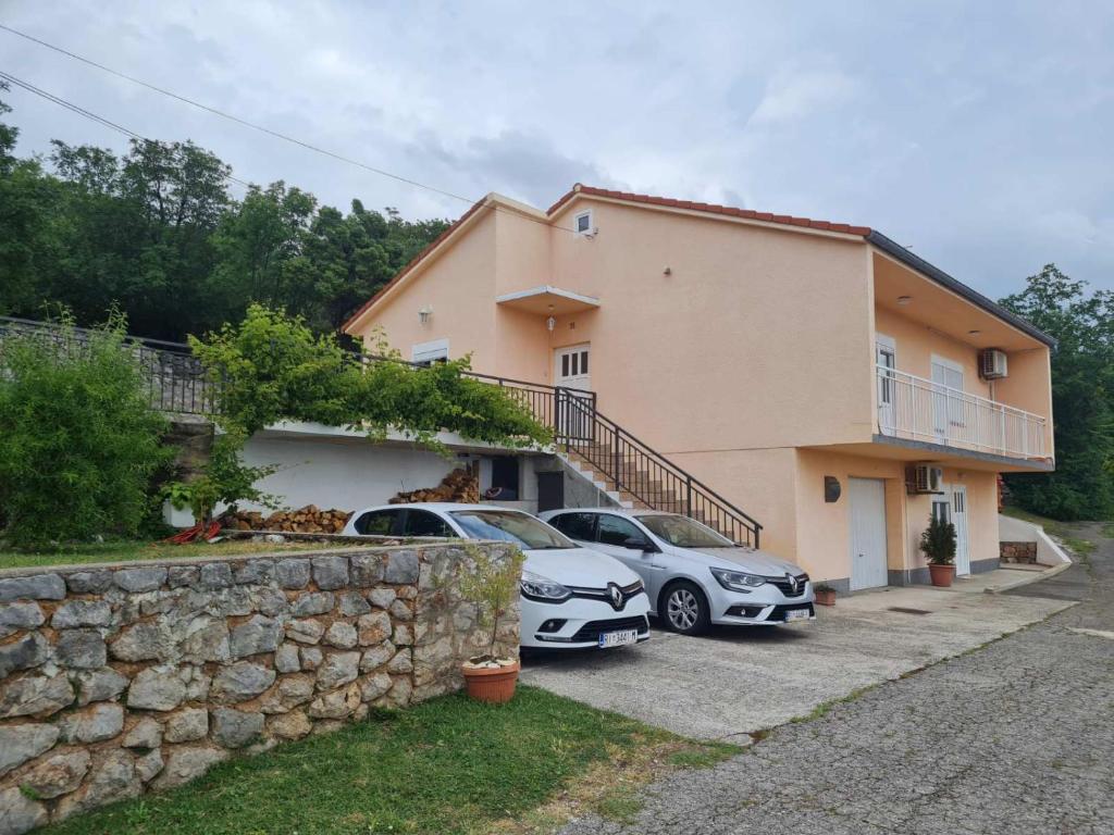 dos autos estacionados frente a una casa en APARTMAN LUKA, en Klenovica