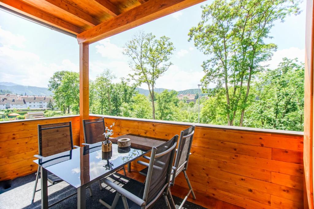 een tafel en stoelen op een balkon met uitzicht op de bomen bij AusZeit Steiraland 7 mit überdachten Balkon und Parkplatz in Judendorf