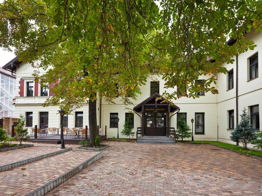 duży biały budynek z ceglanym podjazdem w obiekcie Hotel Braník w Pradze