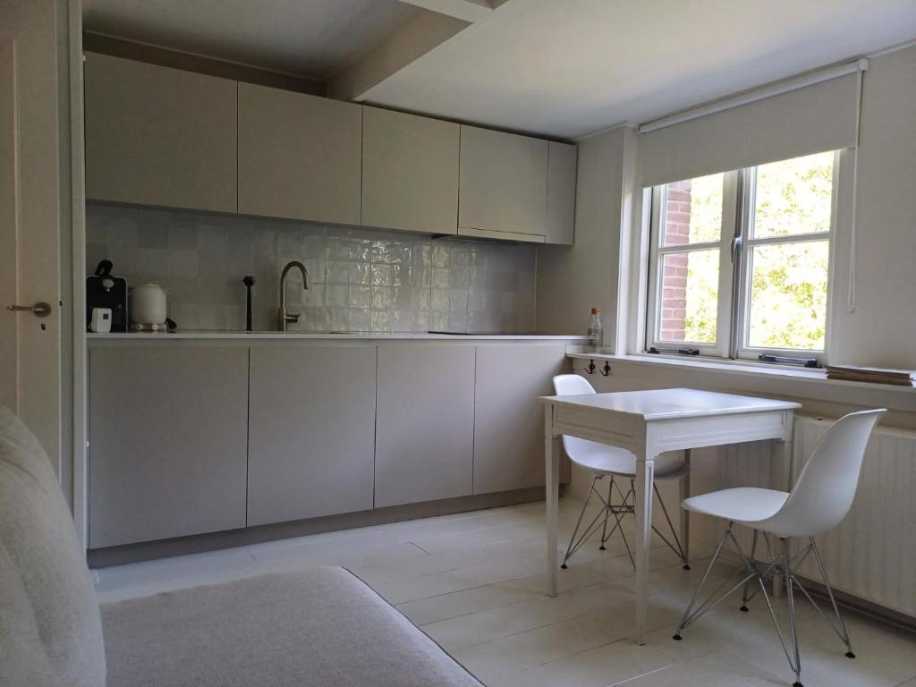 cocina con armarios blancos, mesa y sillas en Vince appartement Culemborg, en Culemborg