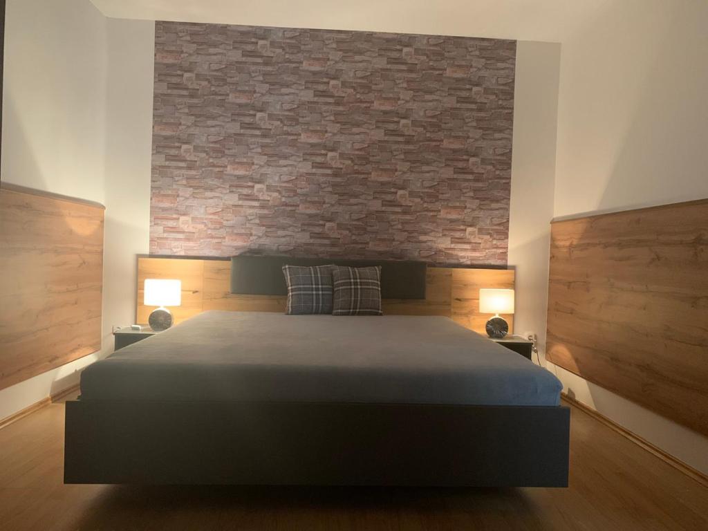 1 dormitorio con 1 cama grande y pared de ladrillo en Braun vendégház, en Sárospatak