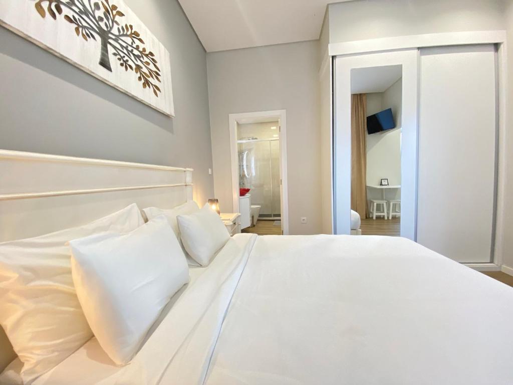 uma cama branca com almofadas brancas num quarto em Canto Doce em Setúbal