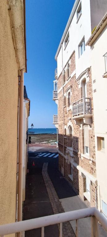 Une allée entre deux bâtiments avec l'océan en arrière-plan dans l'établissement Villa Barriere - Maison a 25m de la Grande plage, à Les Sables-dʼOlonne