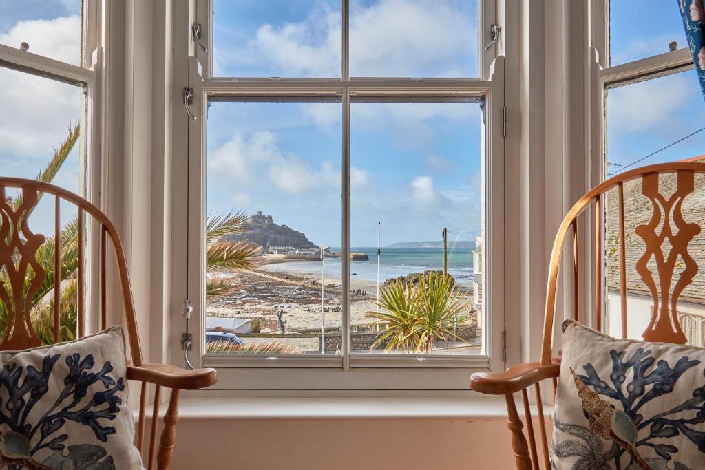 ein Fenster mit Stühlen und Strandblick in der Unterkunft Ocean Villas in Marazion