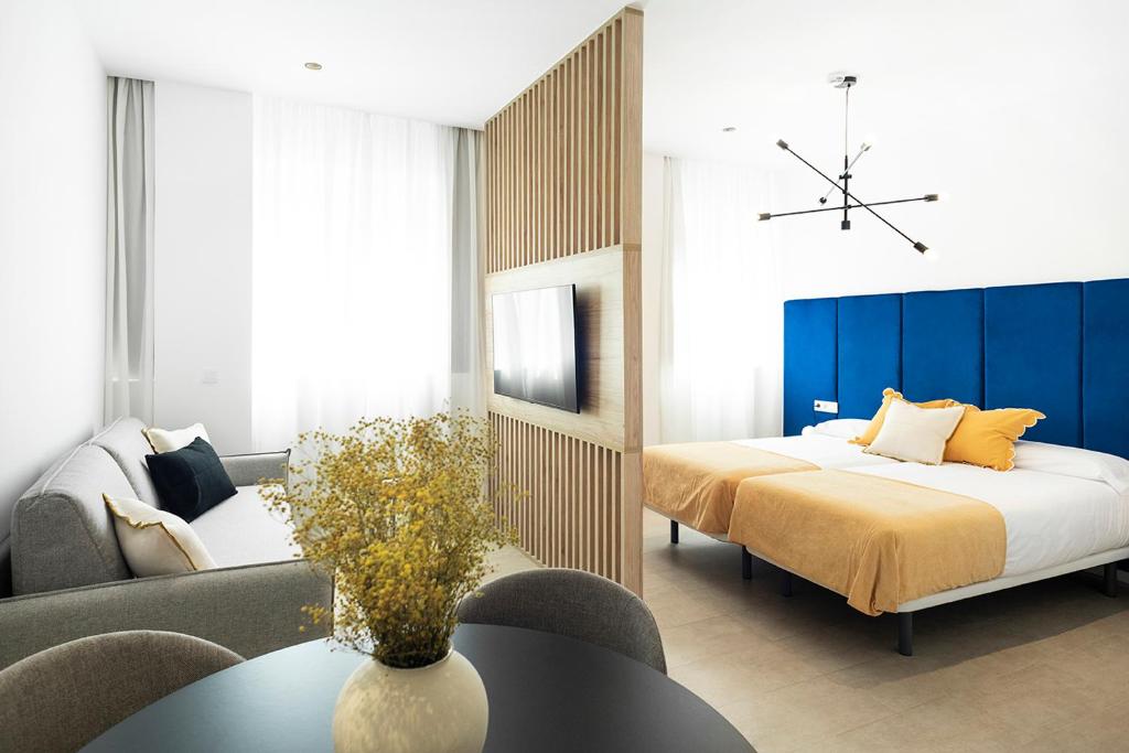 a bedroom with a bed and a couch and a table at Blanq Marina Suites in Valencia