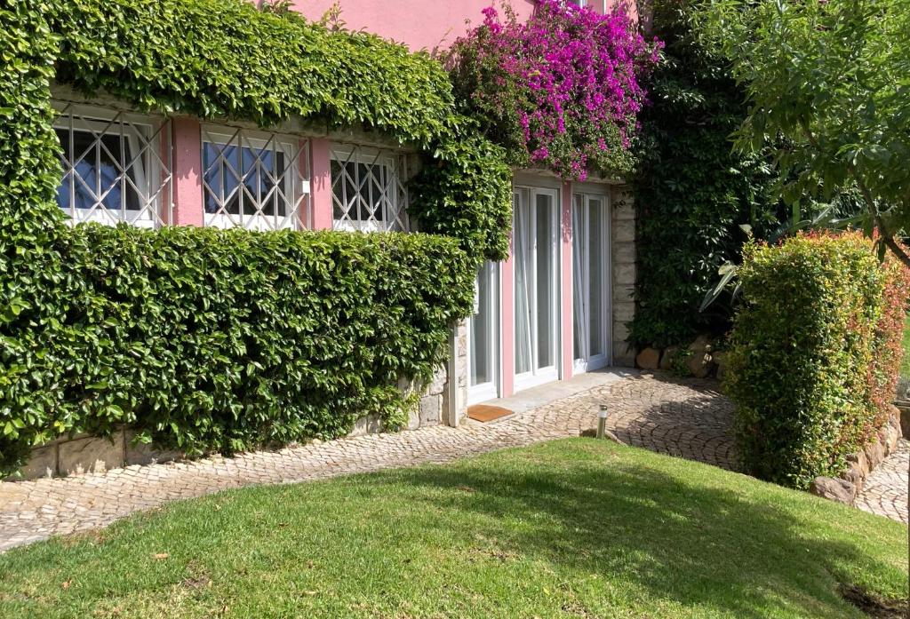a house with a door and some bushes and a yard at Quiet Studio with garden 8 Min from Beach in Estoril