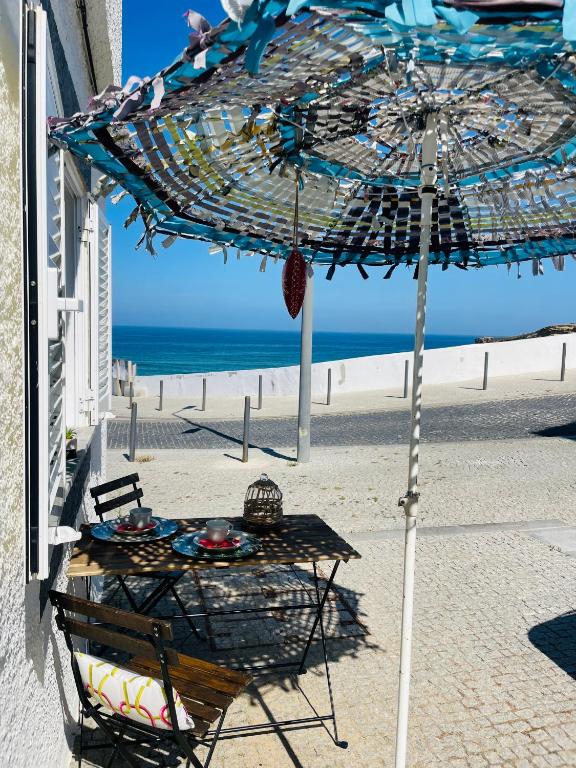 a table under an umbrella on the beach at Zambujeira Lounge in Zambujeira do Mar