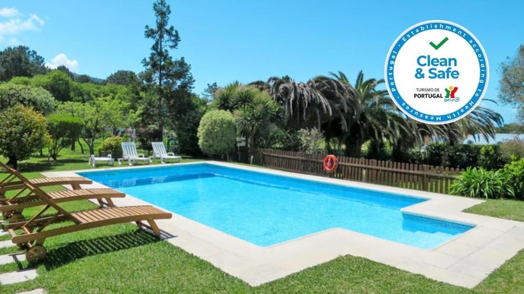 a swimming pool with a bench and a sign that says clean and safe at Fonte do Forno Villas in Afife