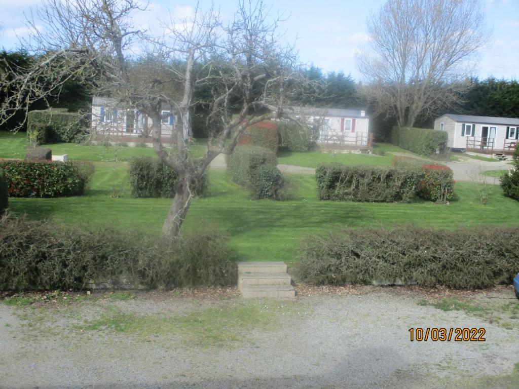 Garlan的住宿－CAMPING VERT DE MORLAIX，享有带灌木和房屋的庭院的景色