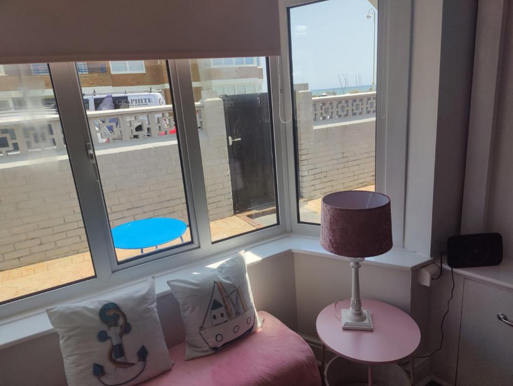 a room with two windows and a pink chair with a lamp at Bexhill Stunning 2 bedroom Sea Front Bungalow in Bexhill