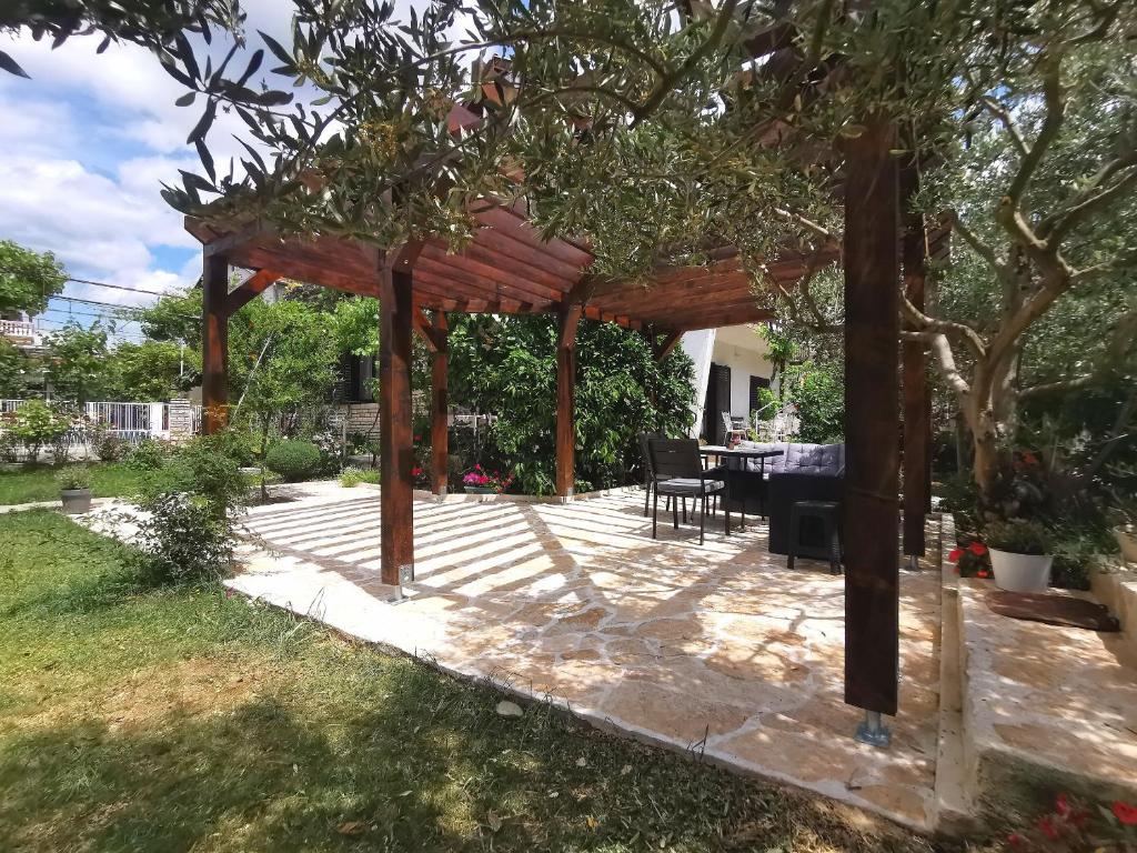 a patio with a wooden pergola in a yard at Apartments Marijana in Vodice