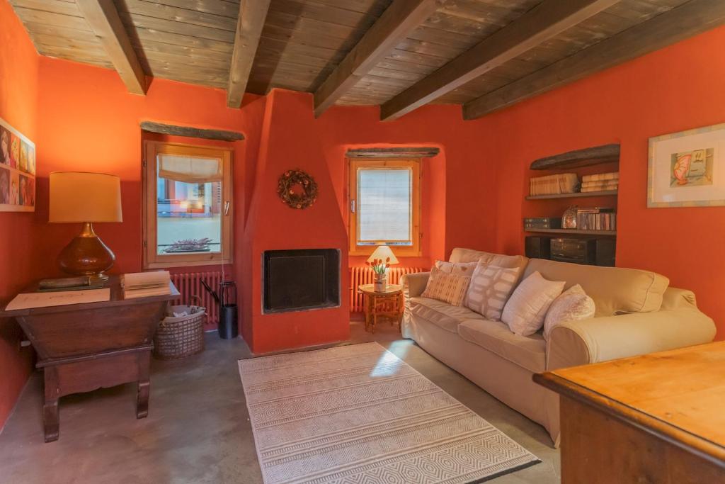een woonkamer met oranje muren en een bank en een tv bij La Corte Degli Artisti by Rent All Como in Blevio