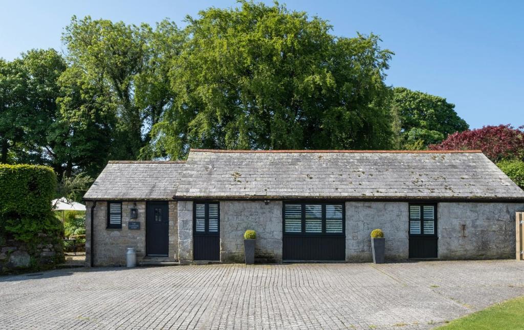 un vecchio edificio in pietra con porte nere e un vialetto di The Lambing Shed, Cornwall ad Altarnun