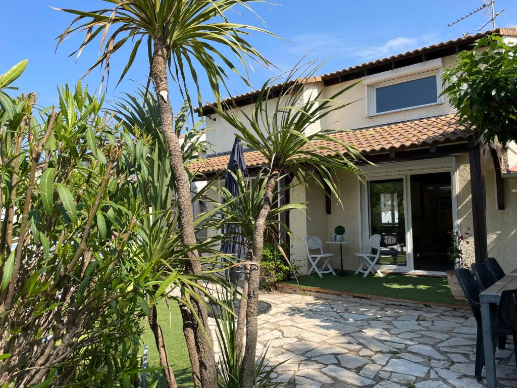 une maison avec des palmiers et une terrasse dans l'établissement Mer Havre de Paix, à Pérols
