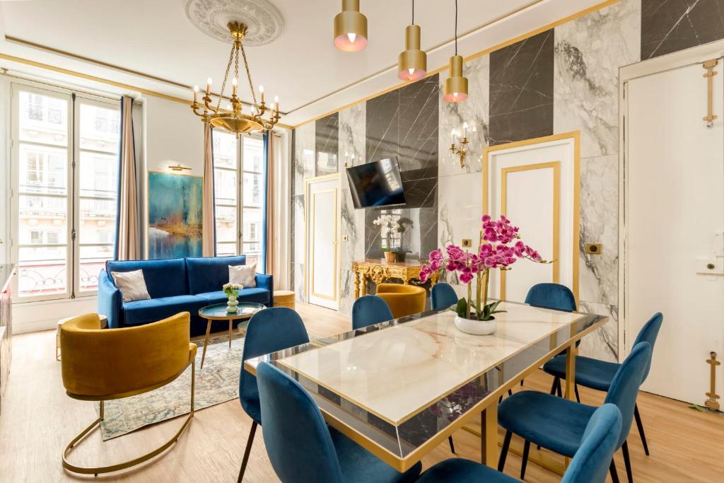 a living room with a glass table and blue chairs at Luxury 3 bedroom 2 bathroom apartment - Louvre in Paris