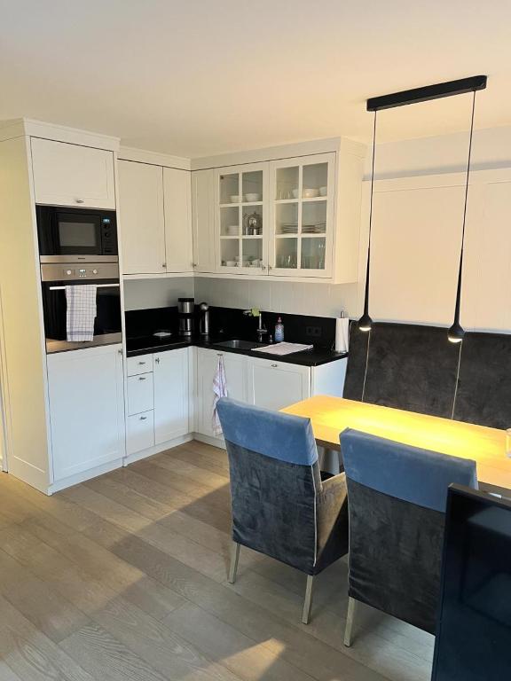 a kitchen with white cabinets and a yellow table and chairs at Stranddüne im Achterhus in Juist