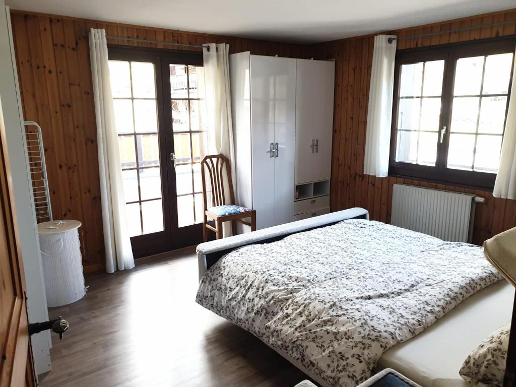 um quarto com uma cama e duas janelas em Les Mélèzes em Val dʼIlliez