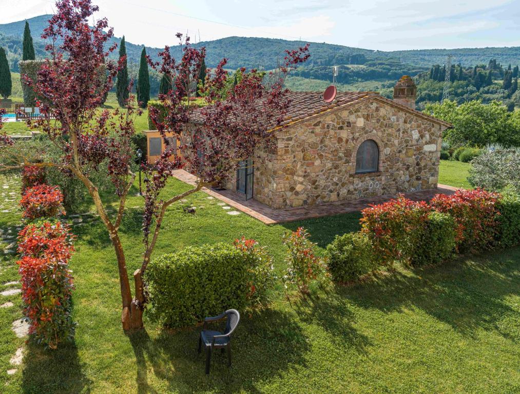 a stone house with a chair in a garden at Agriturismo Scaforno Vacanze in Castelnuovo della Misericordia