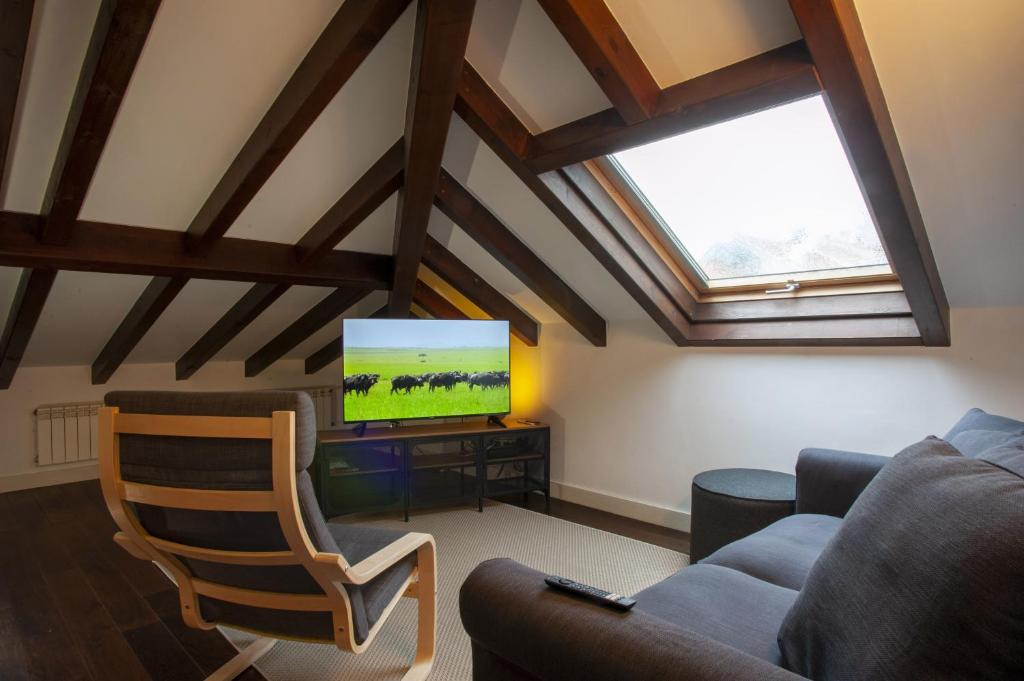 a living room with a couch and a television at Aticos La Riba in Luanco