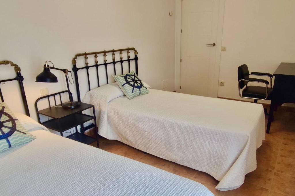sypialnia z 2 łóżkami, biurkiem i krzesłem w obiekcie Apartamento Porto do Xufre w mieście Isla de Arosa