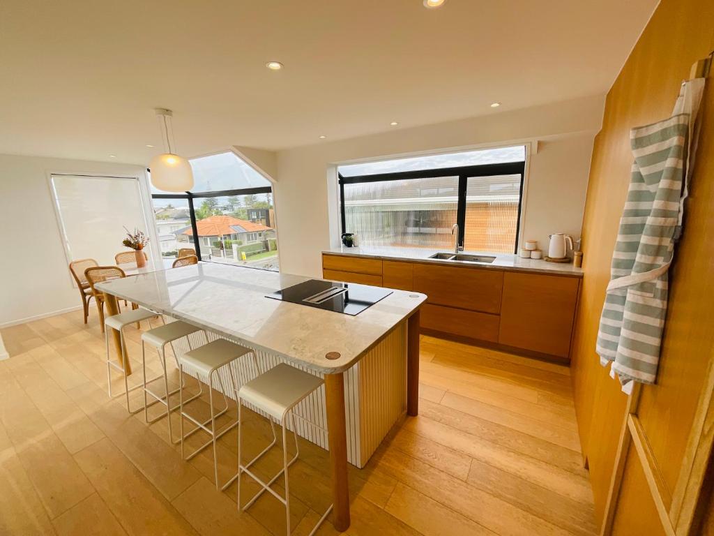 a kitchen with a table and some chairs in a room at Deluxe Downtown Mount Maunganui in Mount Maunganui