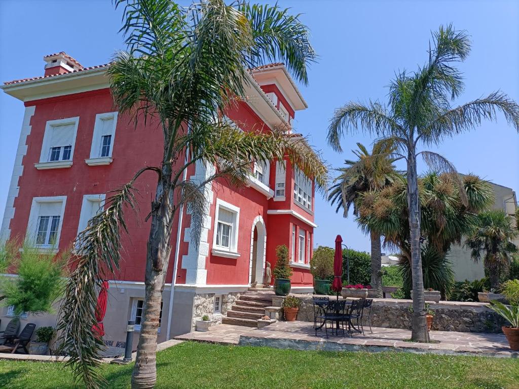 un edificio rojo con palmeras delante en La Torre del Indiano, en Santander