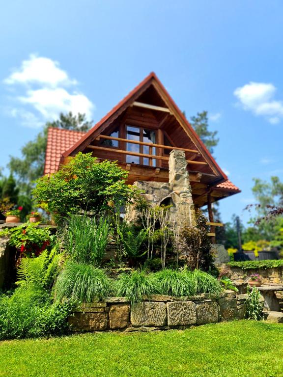 a log cabin with a stone retaining wall in a yard at Domek w Brzezowej in Brzezowa