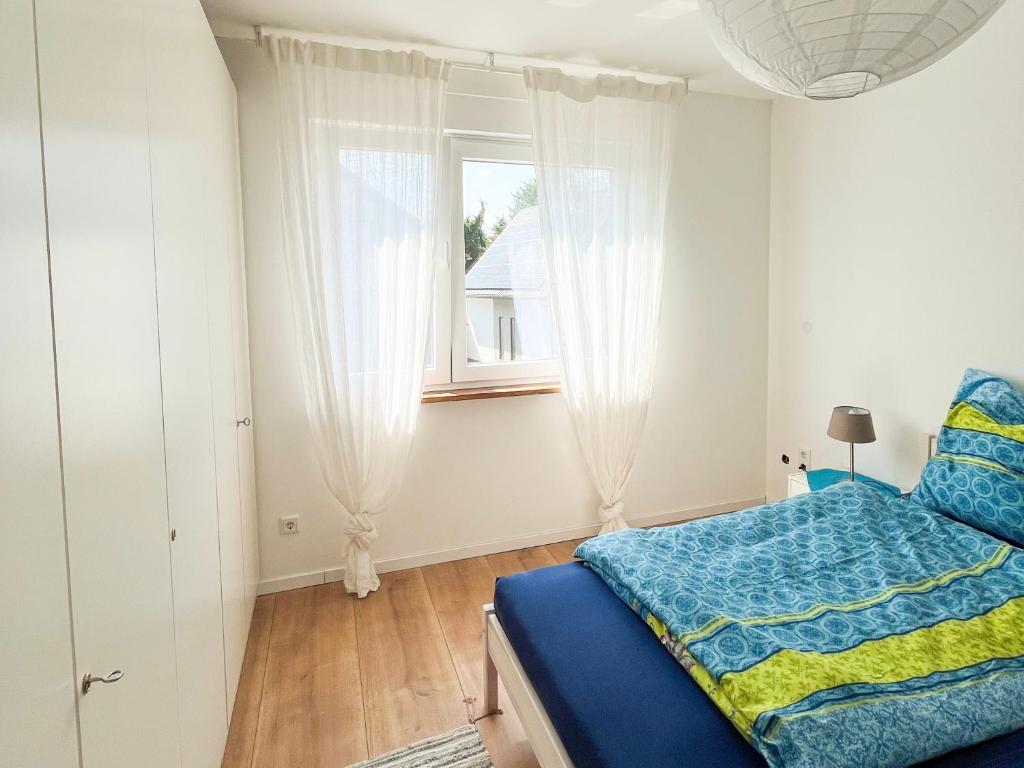 Un dormitorio con una cama azul y una ventana en Helle und gemütliche Ferienwohnung in Lorsch, en Lorsch