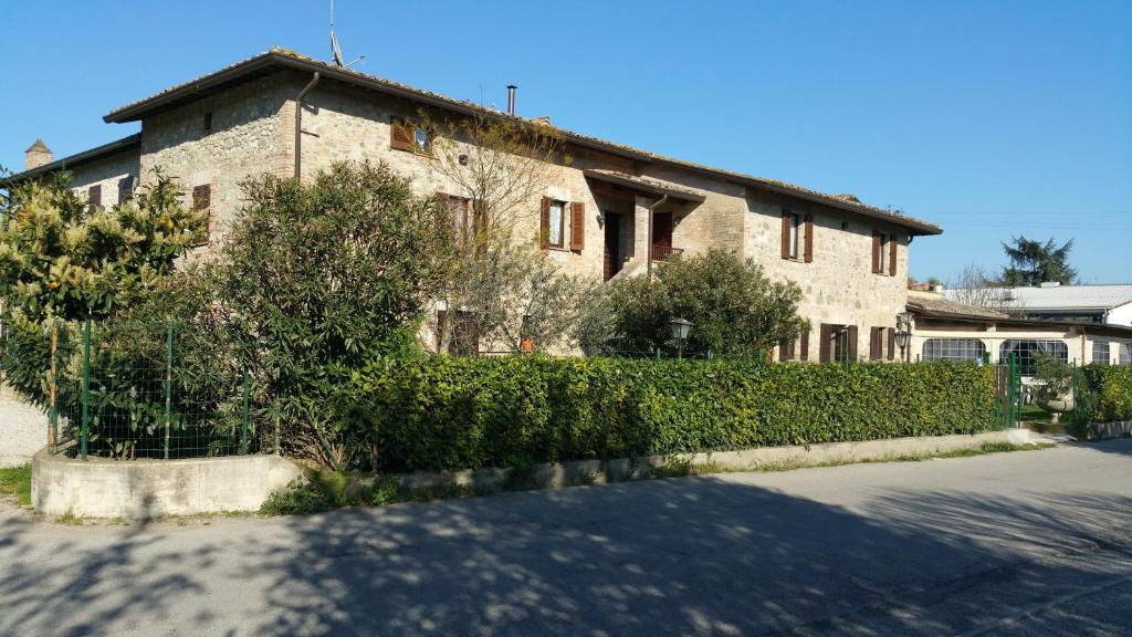 a brick house with bushes in front of a street at Locanda della Braccesca in Ponte Pattoli